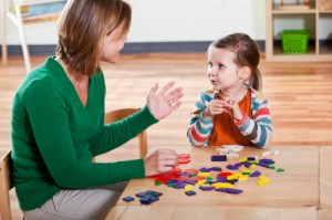 Preschool girl listening to teacher in classroom